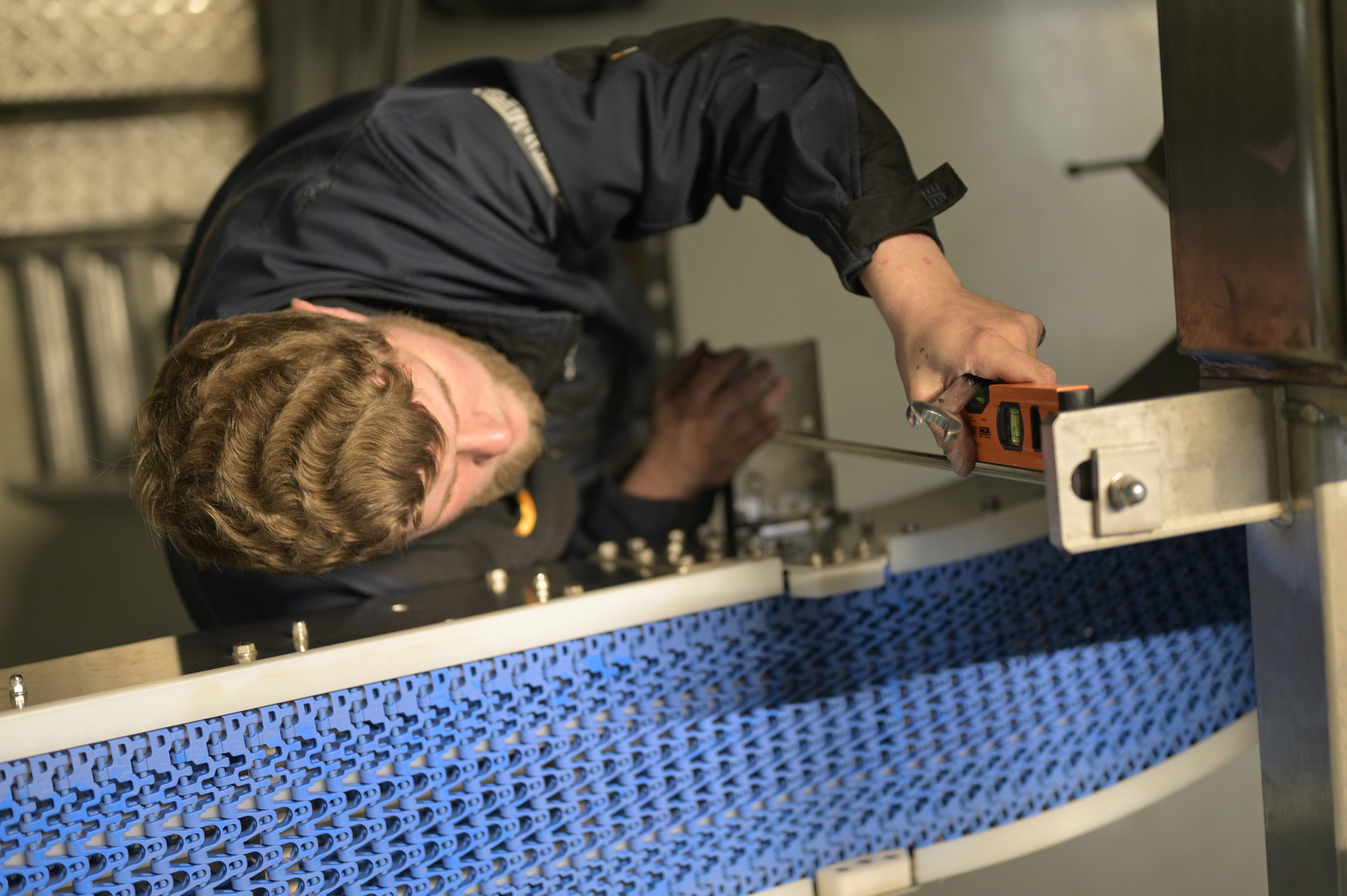 An employee checks the alignment of a pole with a spirit level.