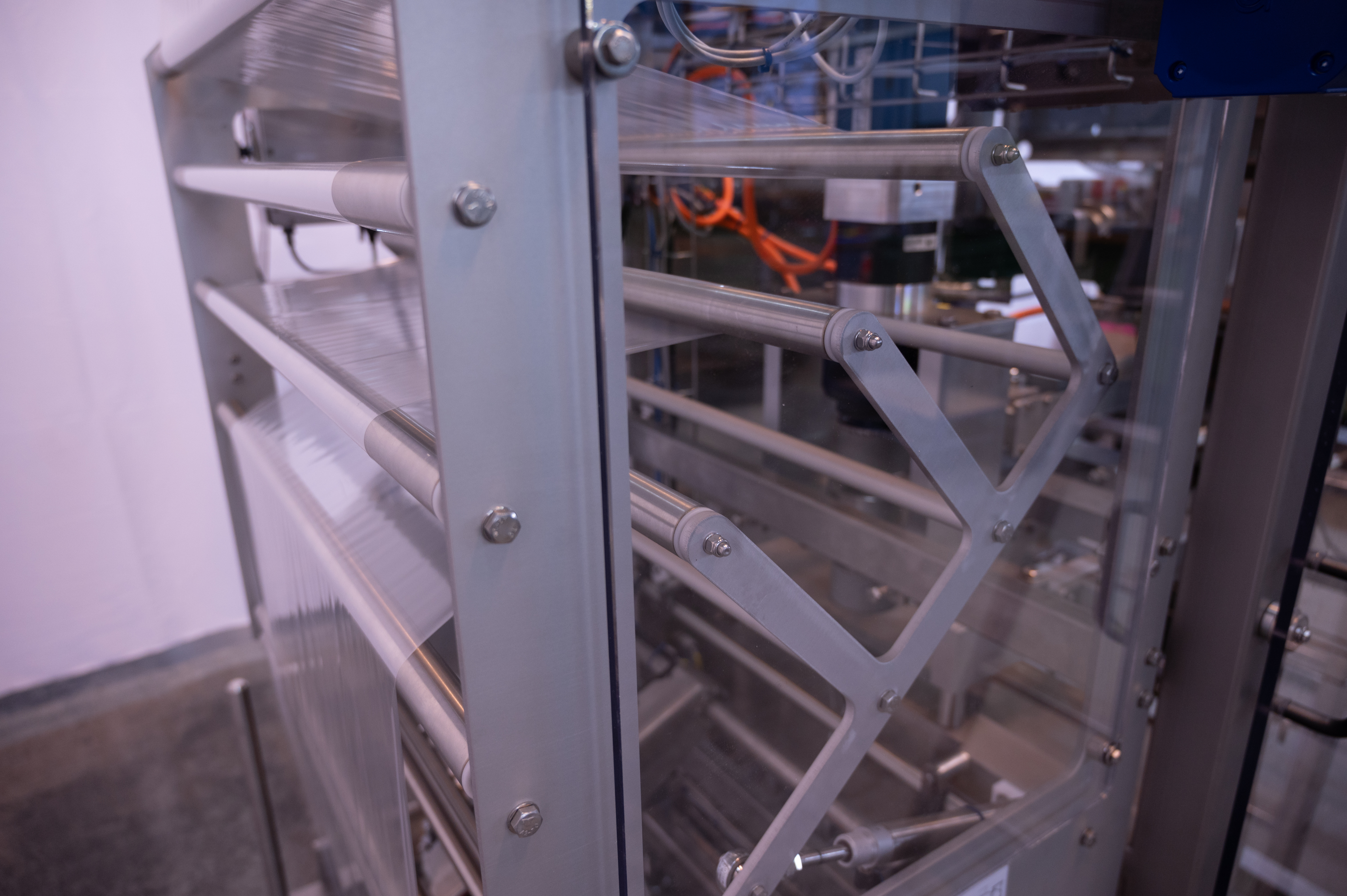 A long strip of transparent film runs on rollers on the AVN E350 SCD form fill and seal machine